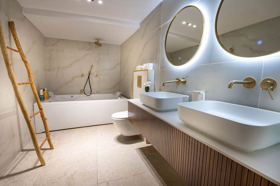 Double-vanity bathroom with backlit mirrors and soaking tub