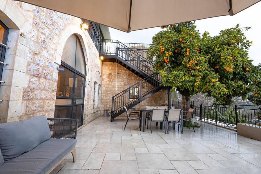Stone facade and staircase beside a citrus tree full of oranges