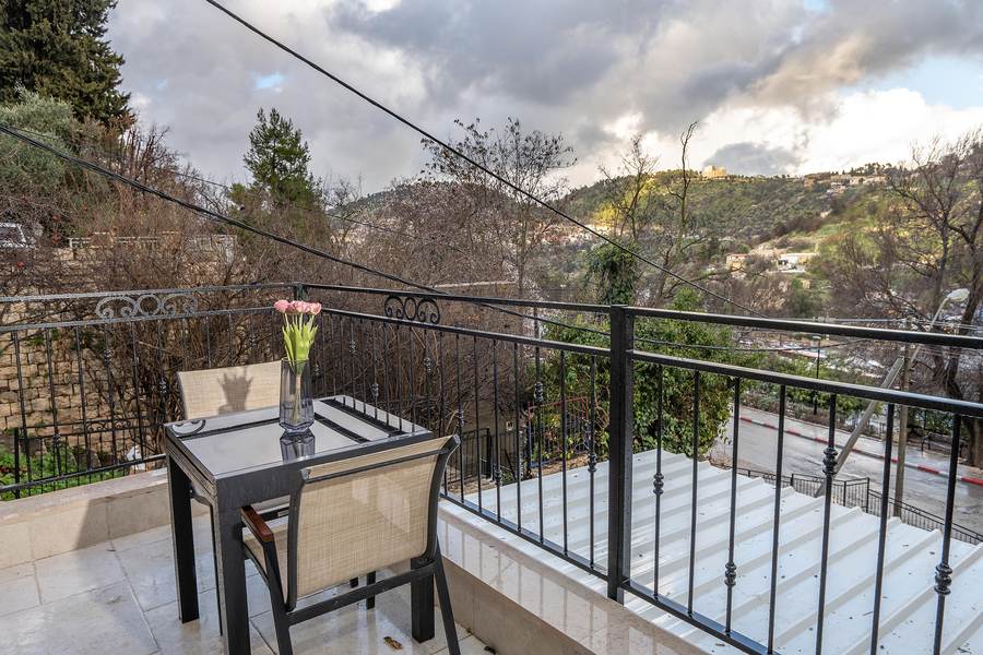 Private balcony table overlooking dramatic hillside sky