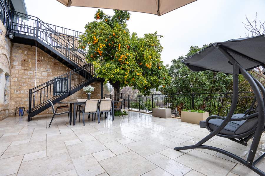 Staircase and terrace with swing chair among citrus trees
